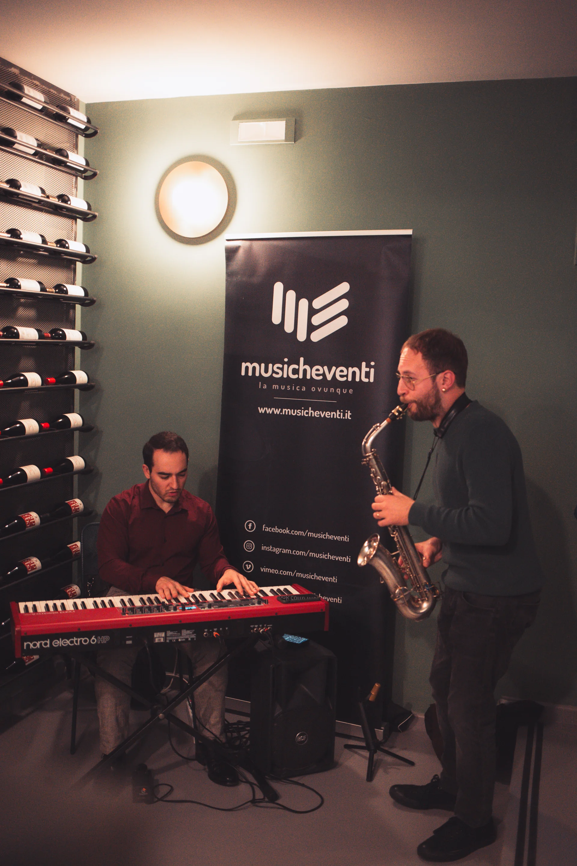 Duo musicale con pianista e sassofonista che si esibisce dal vivo tra le scaffalature di vino
